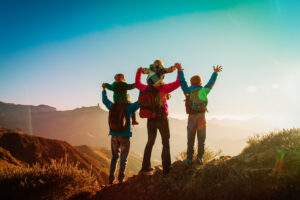 A happy family hiking and enjoying the sunset - mom, dad, and kids.